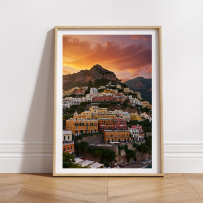 Charming wall art print of Positano, Italy, displaying colorful buildings cascading down a cliffside towards the blue Mediterranean Sea. The print highlights the vibrant pastel hues of the village, surrounded by rugged mountains and lush greenery, capturing the beauty of the Amalfi Coast.